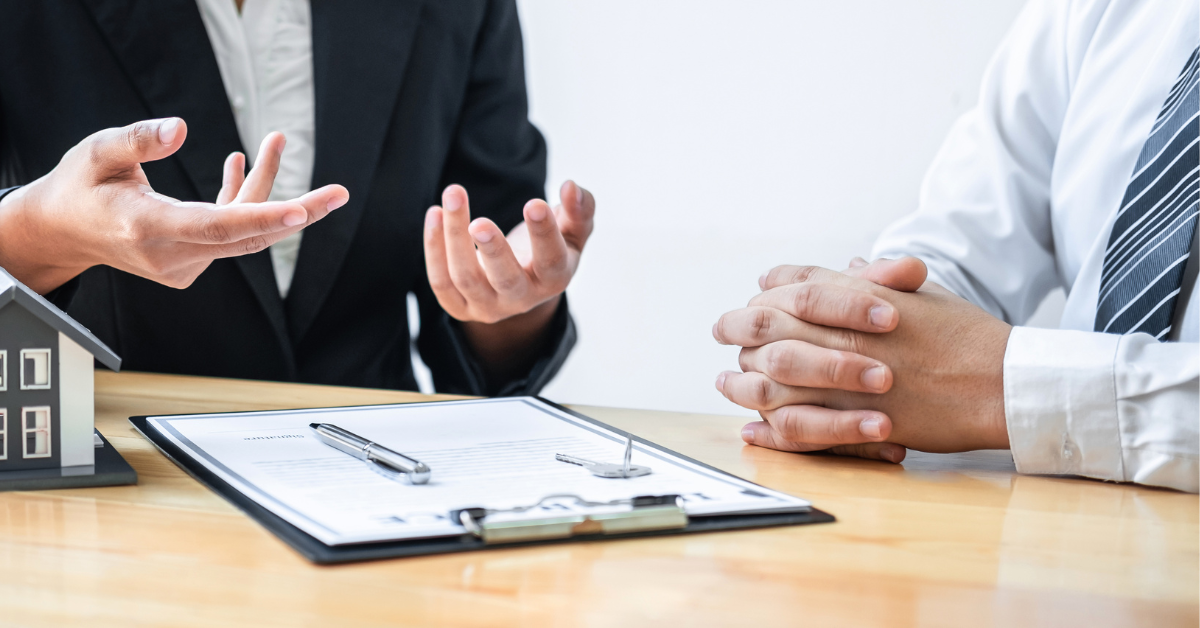 Two people dressed professionally siting at a table with a clip board