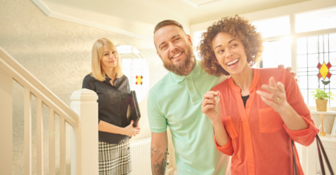 Happy couple in a show home with realtor in background