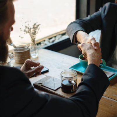 two people shaking hands sitting at a desk