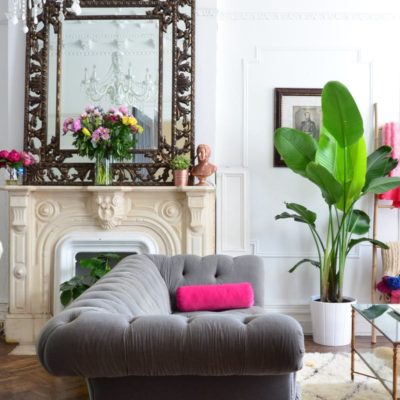 Grey sofa with pink accent pillow and mirror in background